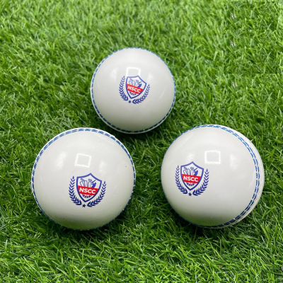 Three cricket balls with a logo on a green grass surface.